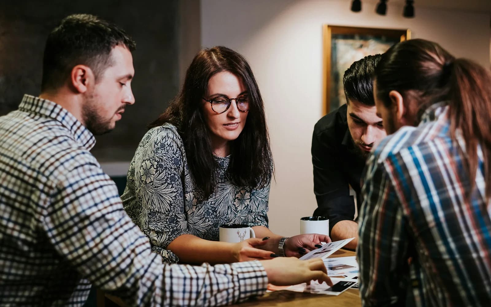 Quatre personnes étudient des documents autour d'une table