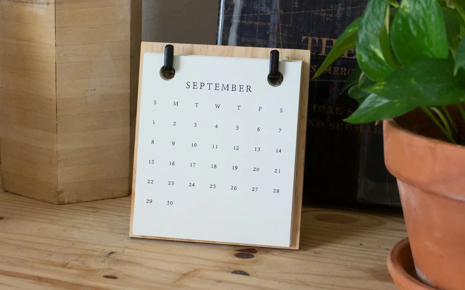 Calendrier de bureau ouvert sur le mois de septembre, à côté d'une plante